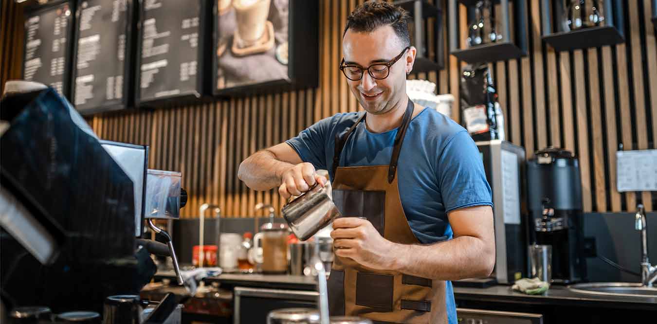 a male barista making coffee at a shop